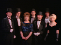 The seven members in tuxedos, top hats and evening dresses
