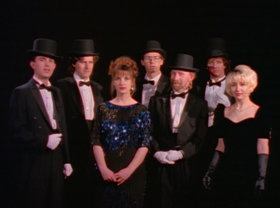 The seven members in tuxedos, top hats and evening dresses